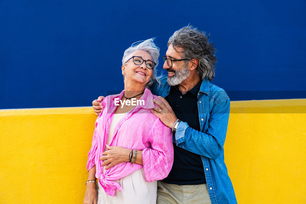 portrait of smiling friends standing against blue wall