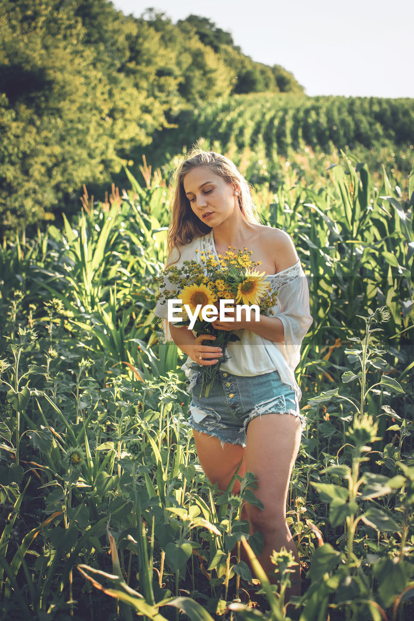  young woman holding bouquet standing in field