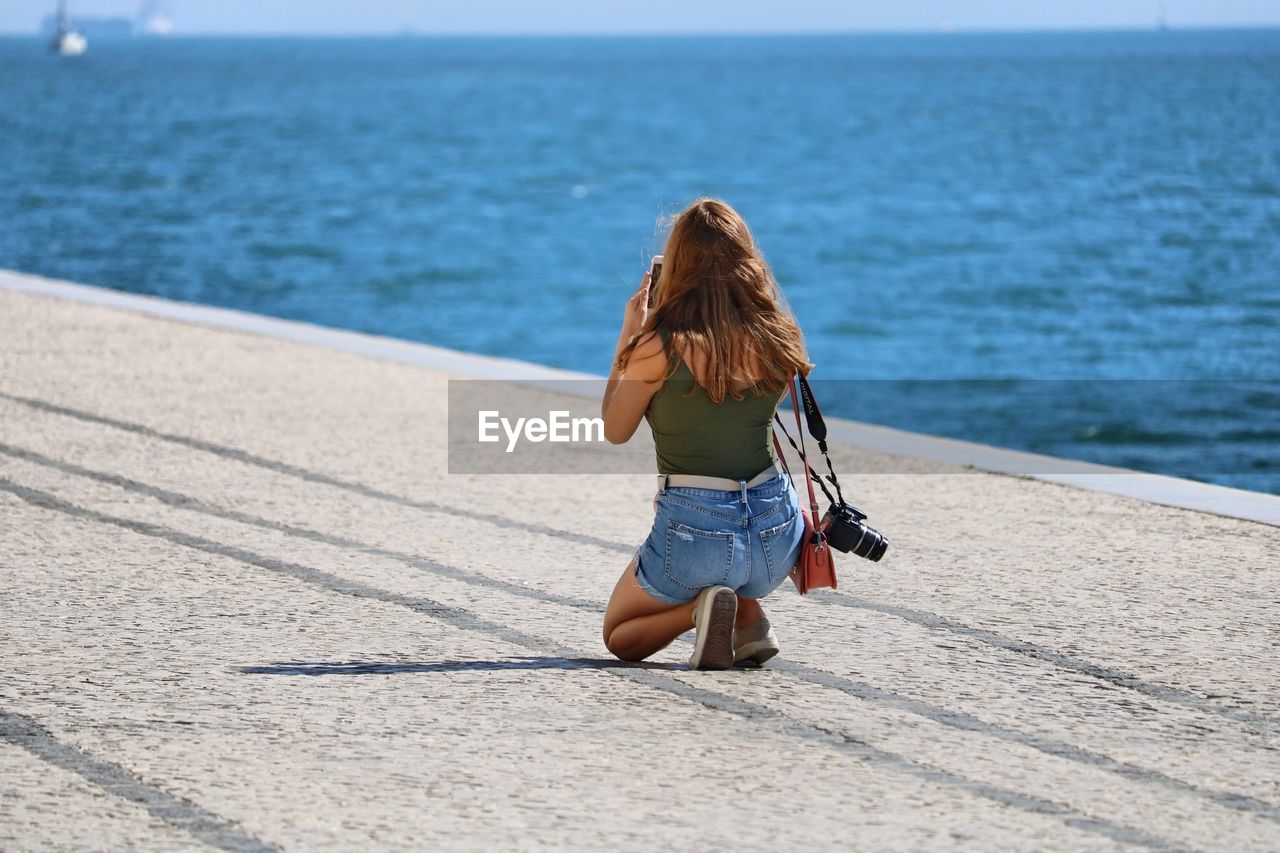 Woman kneeling at beach in city