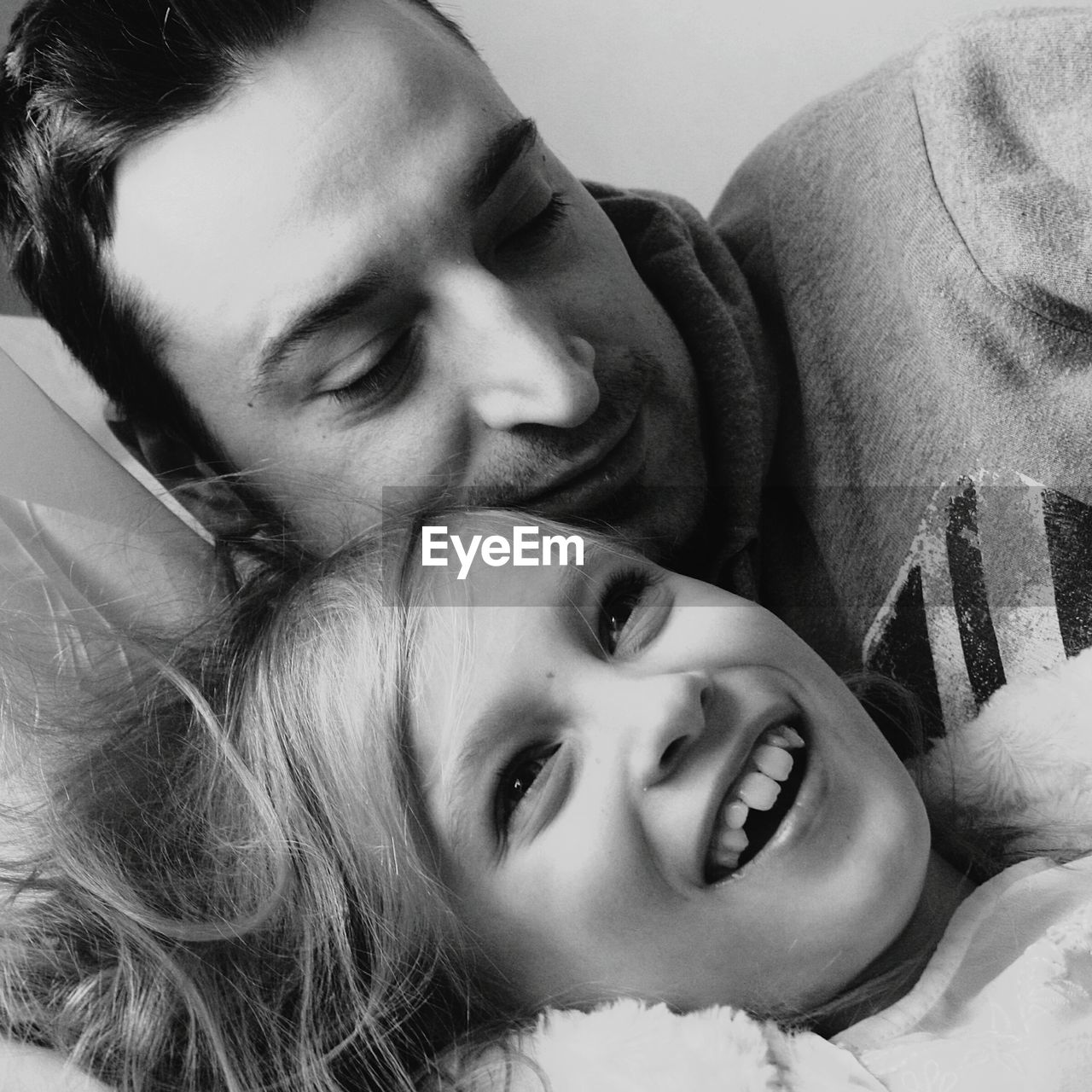 Close-up of happy daughter and father lying on bed at home