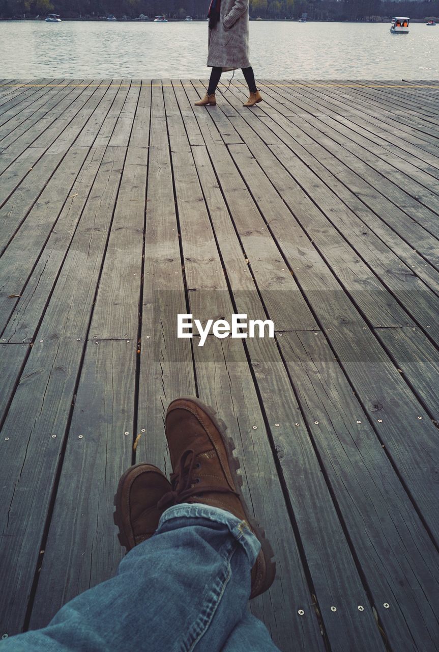 LOW SECTION OF MAN STANDING ON WOODEN PIER