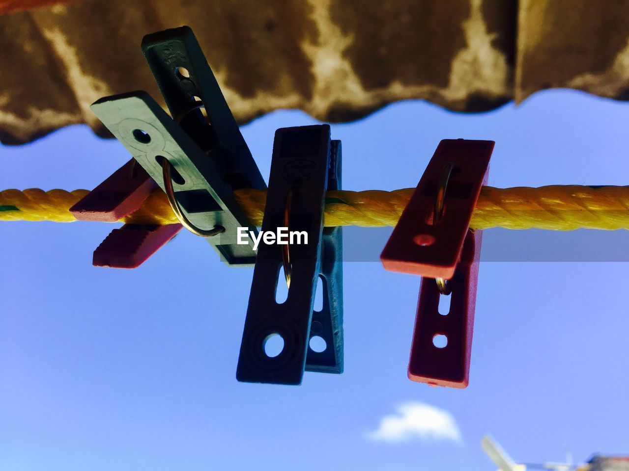 LOW ANGLE VIEW OF CLOTHESPINS HANGING AGAINST SKY