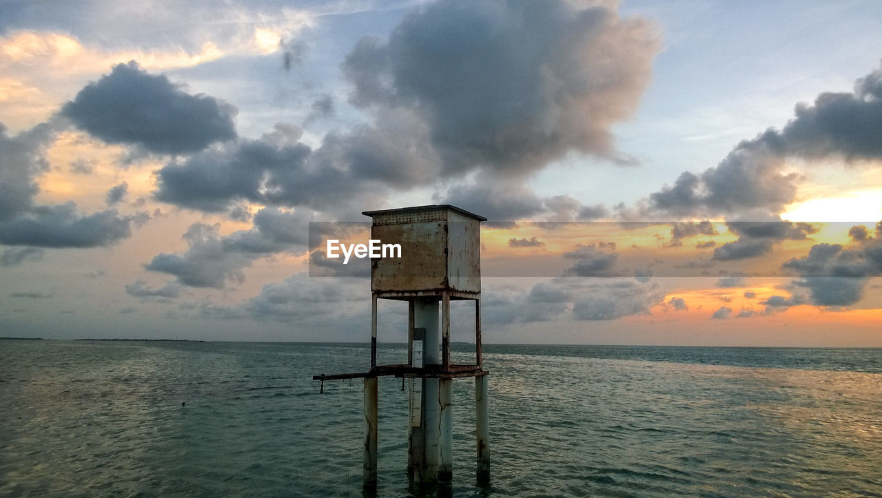 Lifeguard hut on sea against sky during sunset