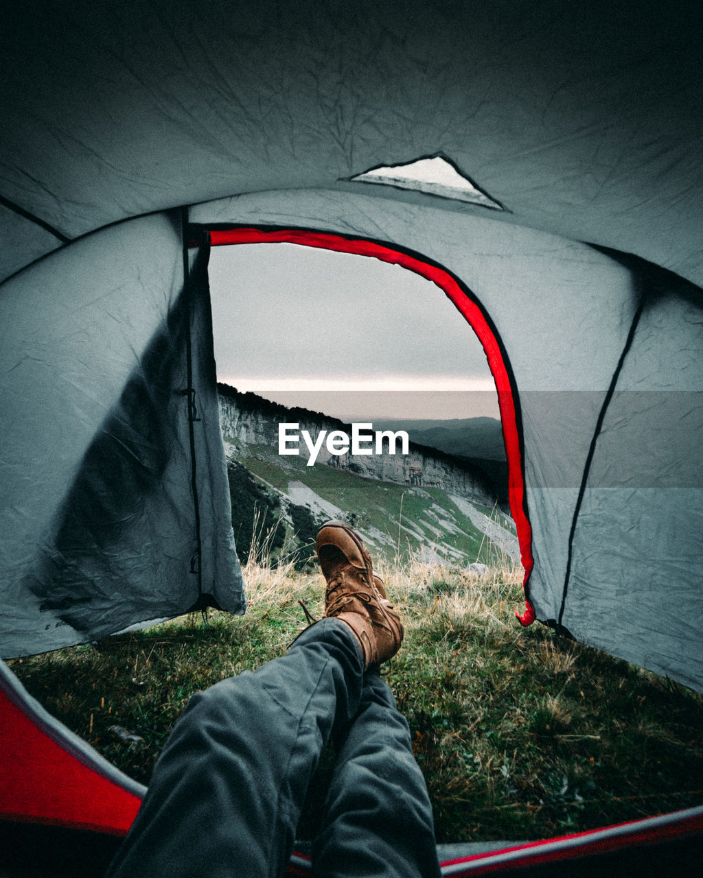 Low section of man relaxing in tent on mountain