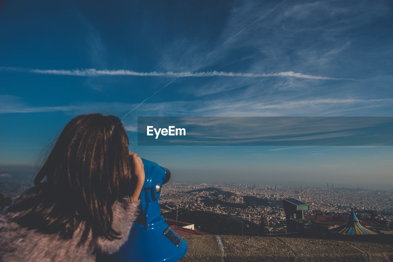 REAR VIEW OF WOMAN PHOTOGRAPHING AGAINST SKY