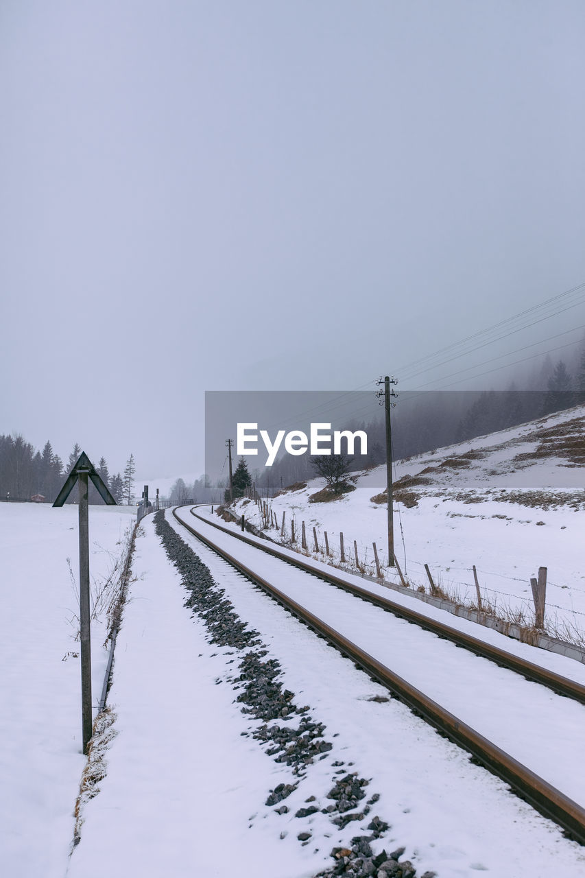 Snow covered railroad tracks against sky