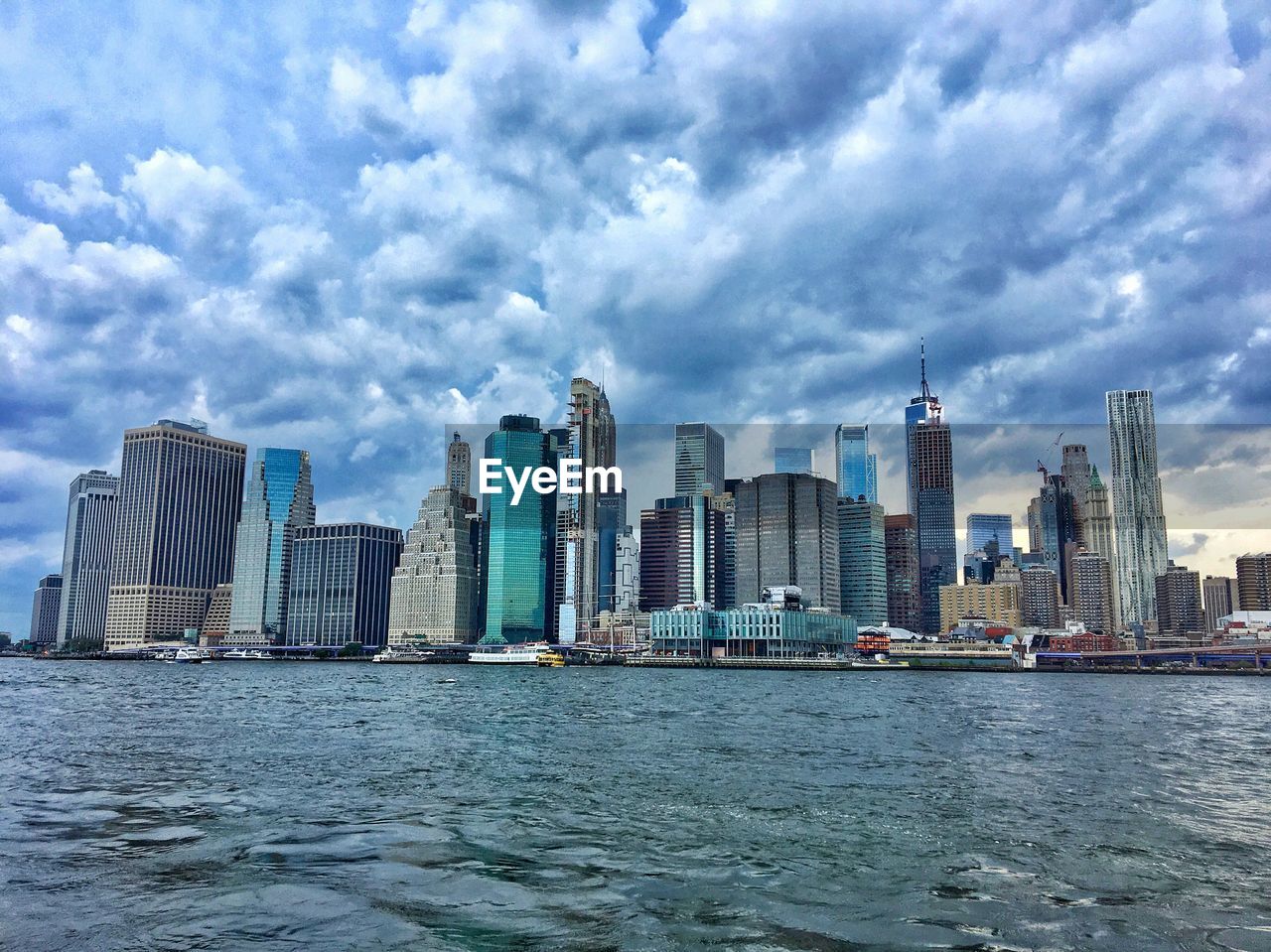 Sea and buildings in city against cloudy sky