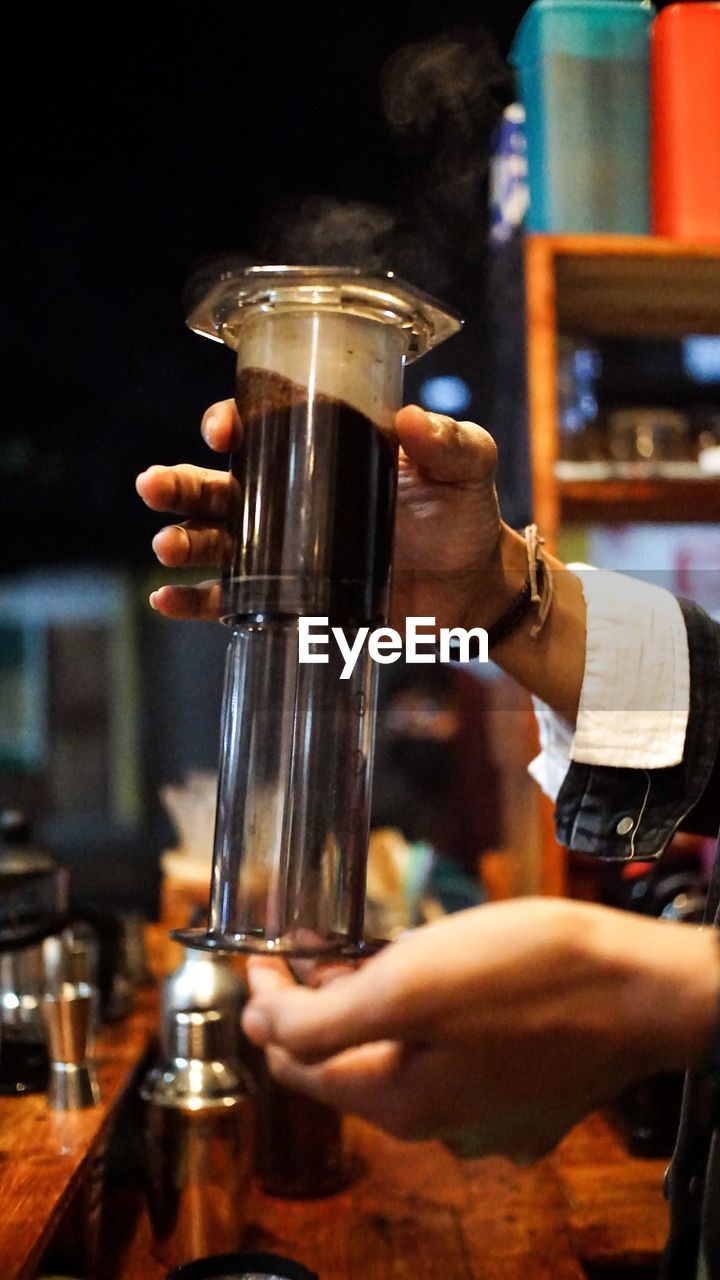 Midsection of man holding aeropress coffee 