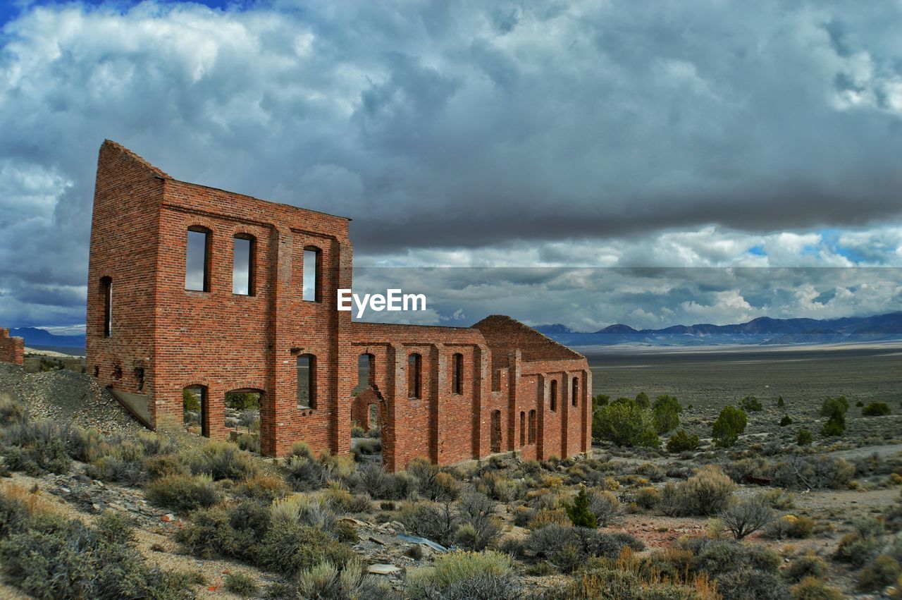Old ruin building on field against cloudy sky
