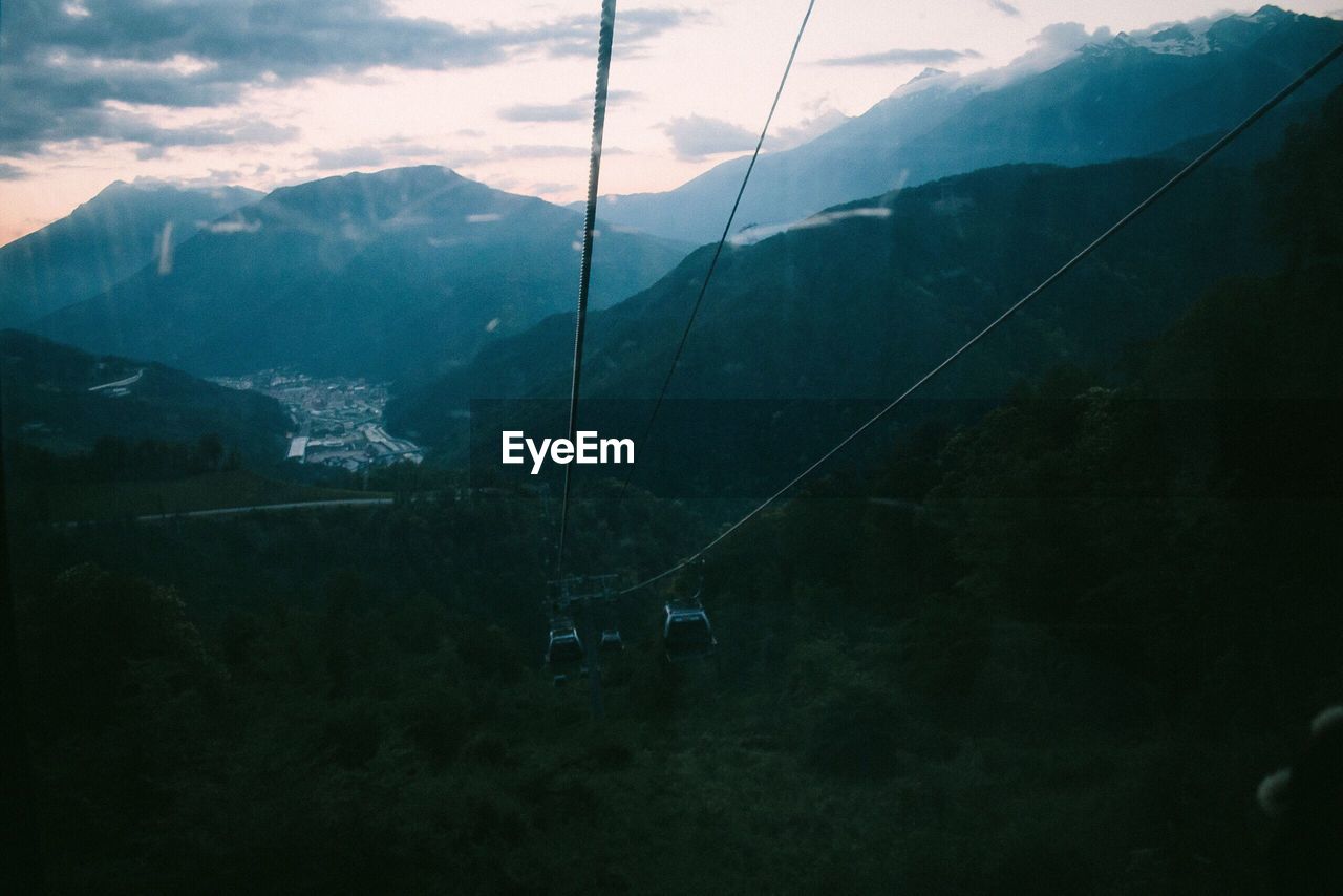 Overhead cable cars hanging against mountain range