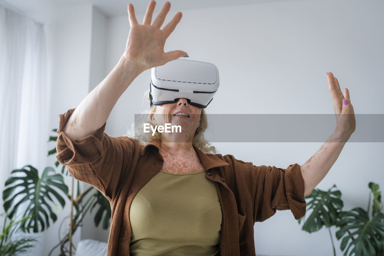 Senior woman with vitiligo skin wearing virtual reality headset at home