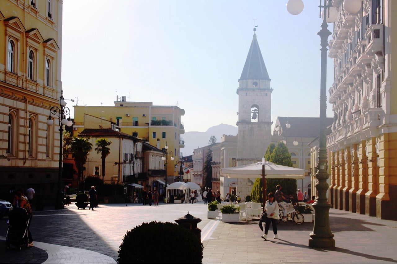 PEOPLE WALKING IN TOWN SQUARE AGAINST SKY