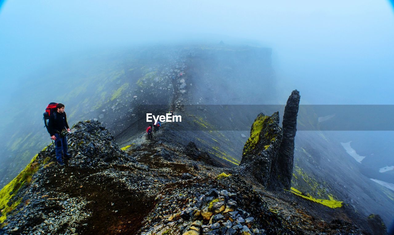 High angle view of people hiking on mountain during foggy weather