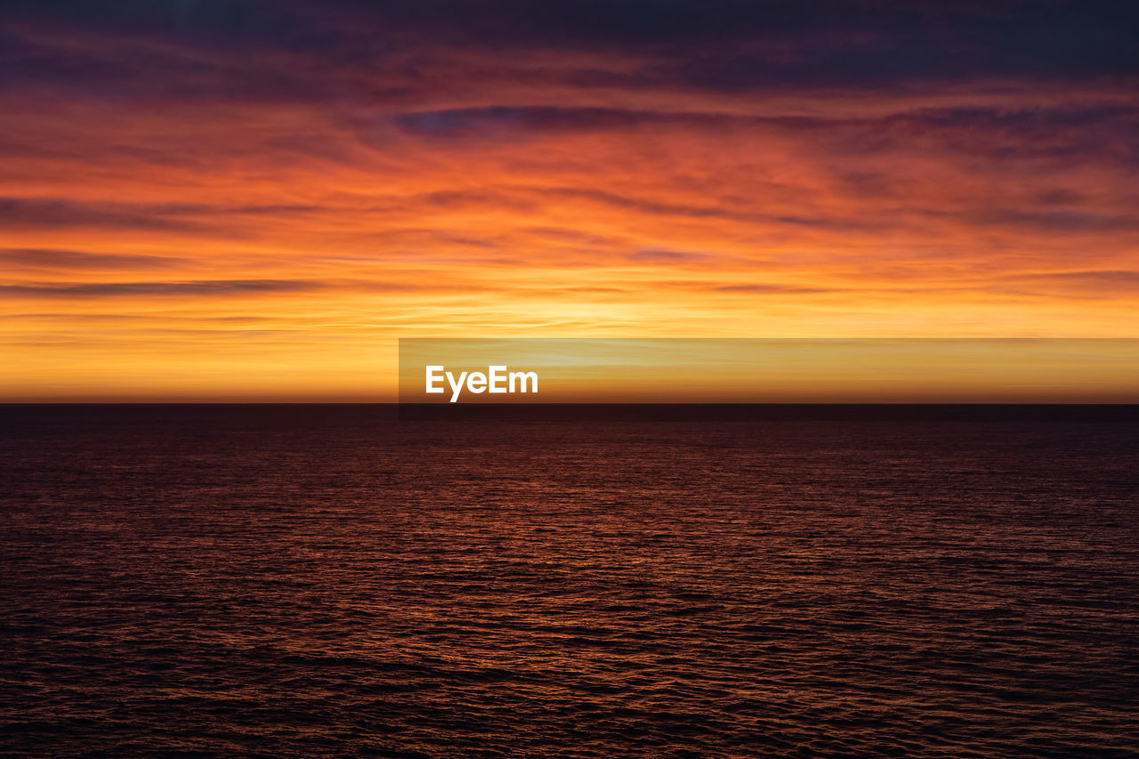 Orange and pink sky above ocean horizon