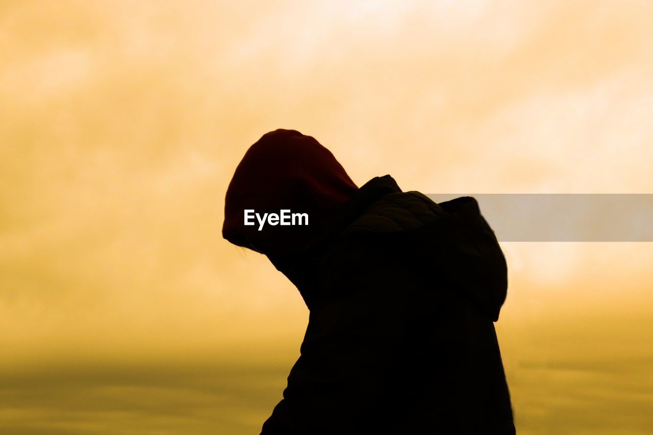 Silhouette man standing against orange sky