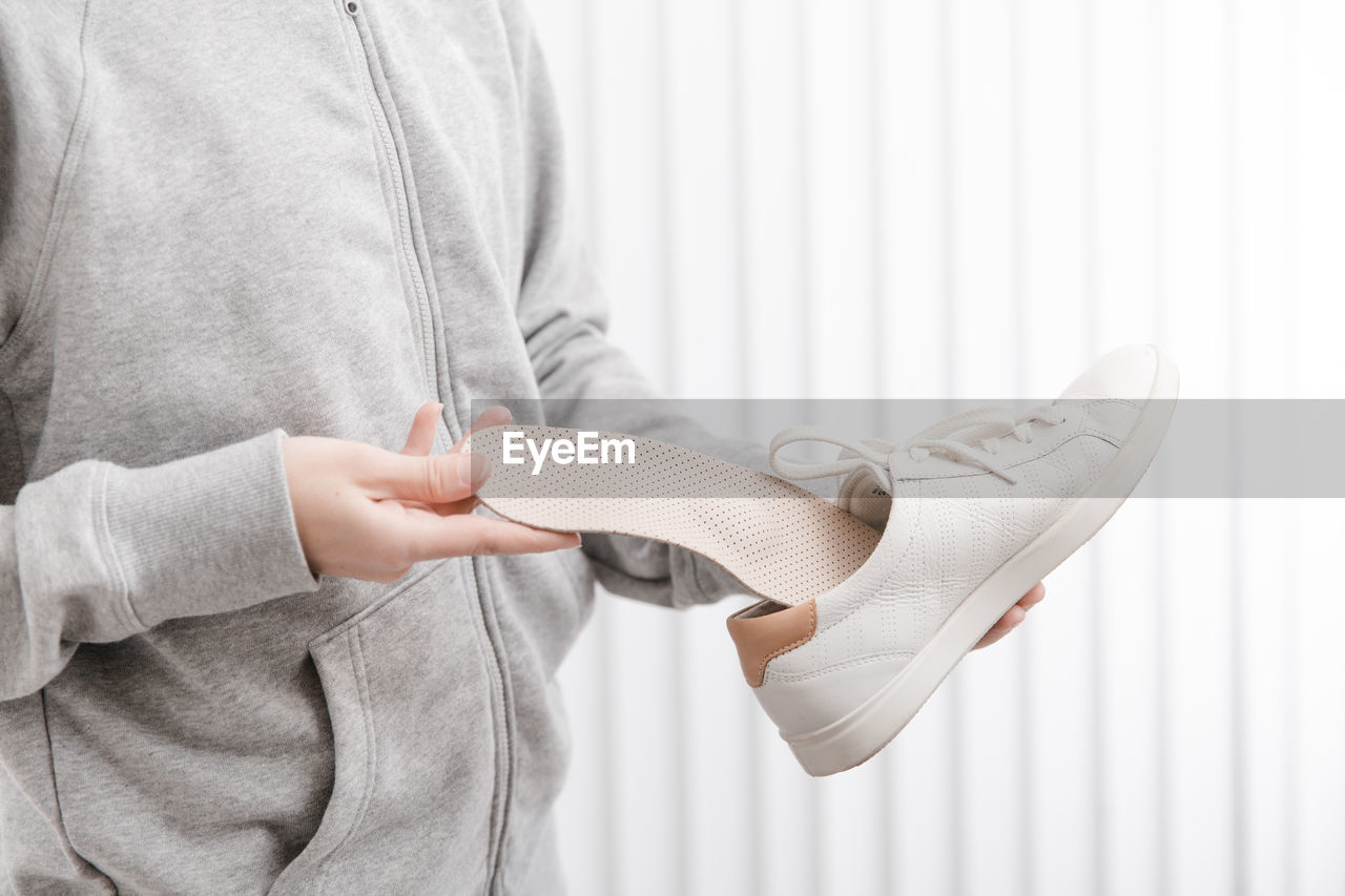 Midsection of woman inserting insole in shoe