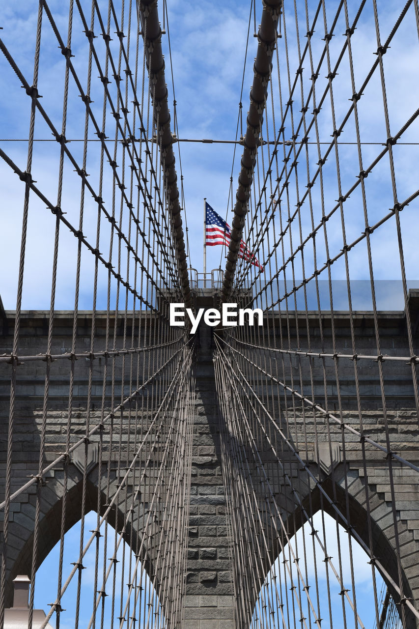 Low angle view of american flag on brooklyn bridge against sky