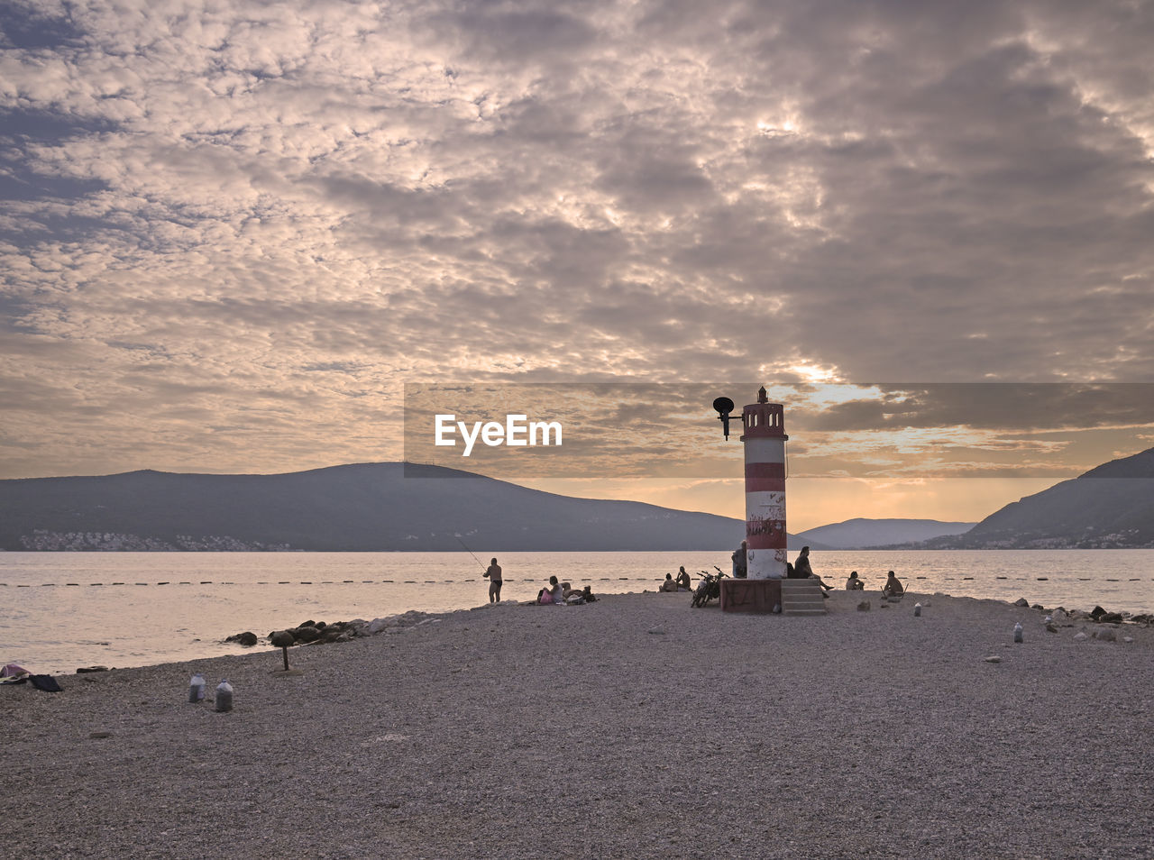 lighthouse, sky, sea, water, beach, guidance, horizon, architecture, land, coast, ocean, tower, built structure, nature, cloud, building exterior, shore, security, building, protection, sunset, scenics - nature, travel destinations, sand, coastline, dawn, beauty in nature, travel, environment, landscape, body of water, wave, tranquility, evening, bay, outdoors, mountain, silhouette, tranquil scene, water's edge, holiday, trip, tourism, vacation, no people, non-urban scene, dramatic sky, sunlight, sand dune, seascape