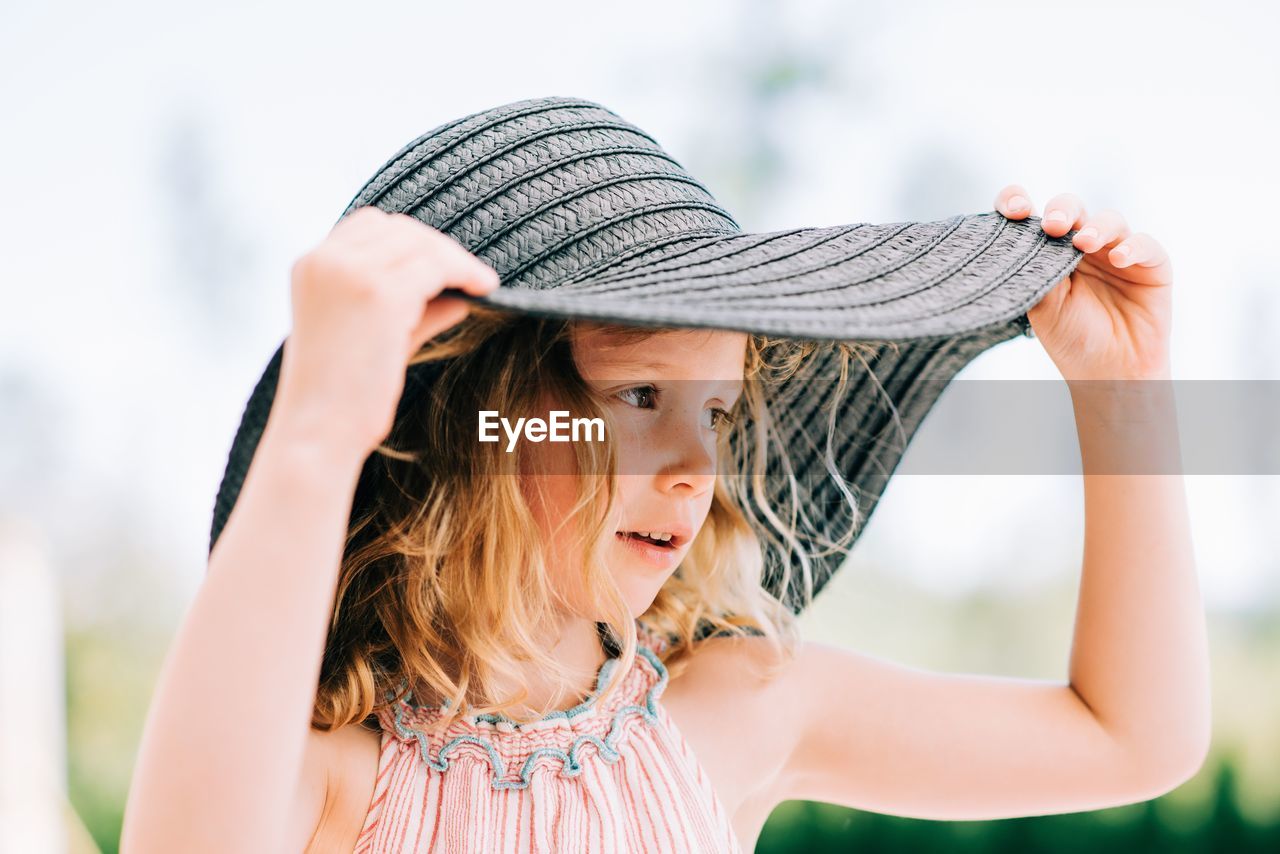 Candid portrait of a young girl wearing a sunhat outside