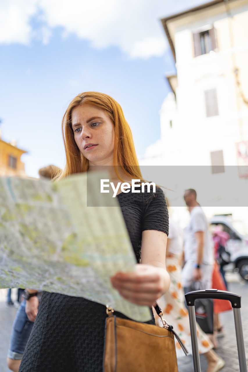 Red hair woman look a map during a travel in city centre