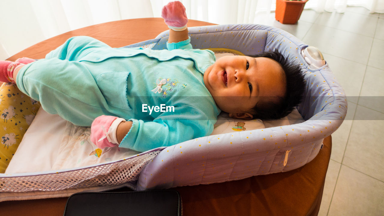High angle view of smiling toddler lying on bed at home