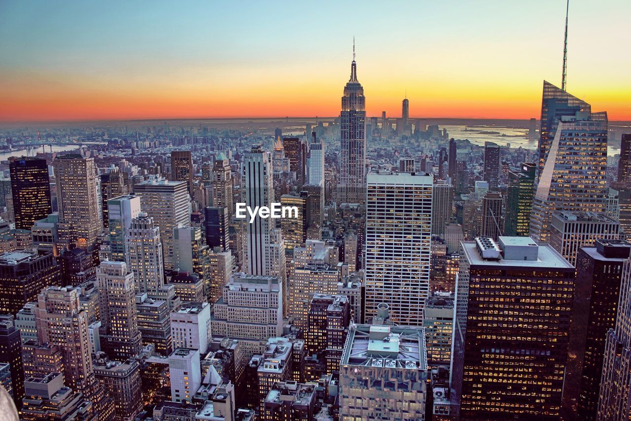 Empire state building and city against sky at dusk