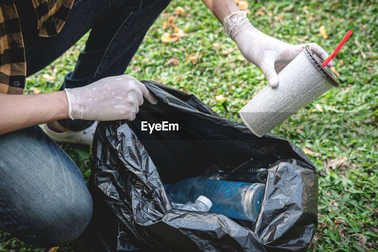 low section of man cleaning garbage in garden