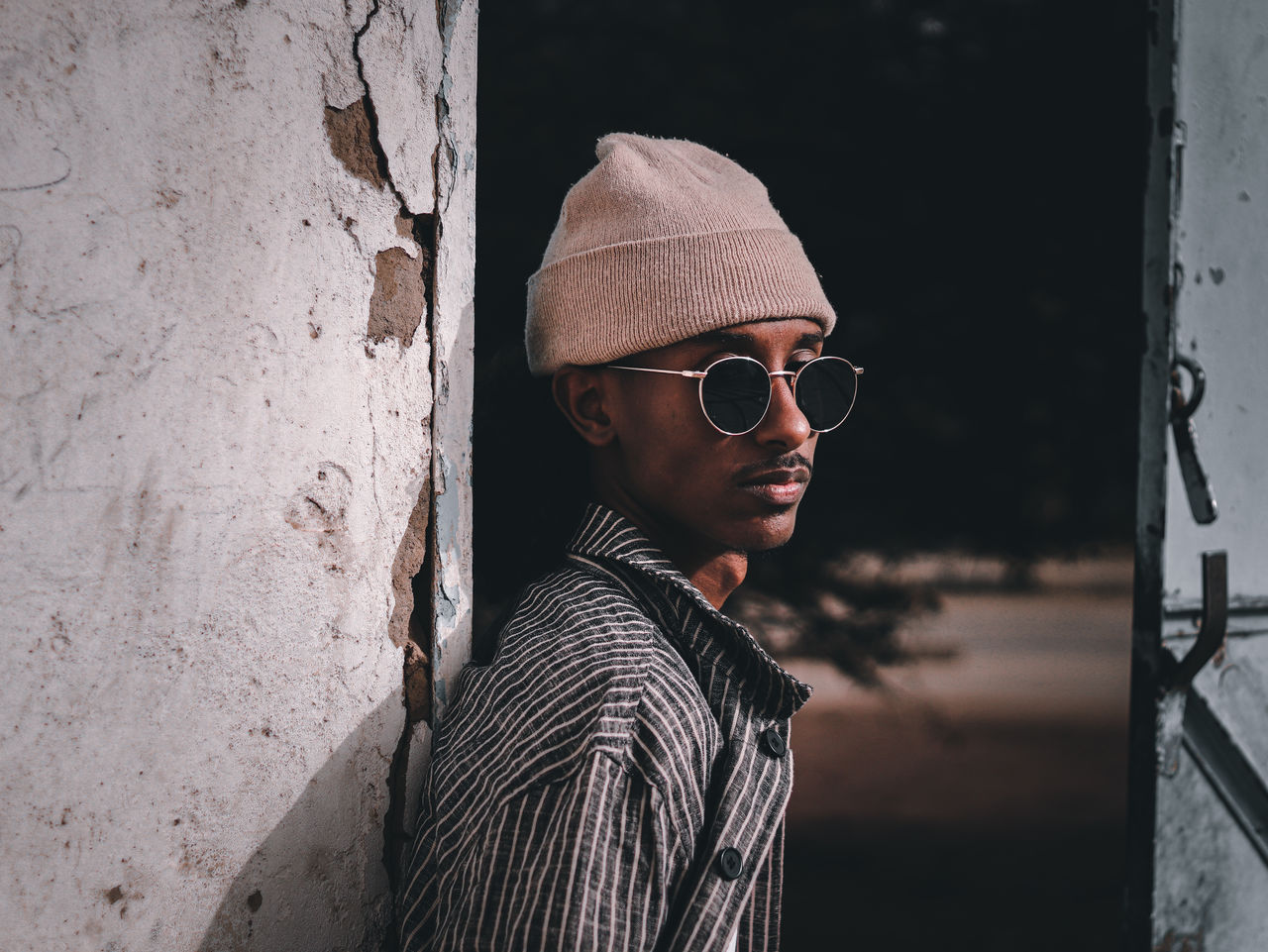 Portrait of young man wearing sunglasses standing against wall