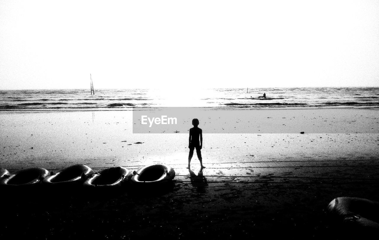 REAR VIEW OF PEOPLE ON BEACH AGAINST SKY