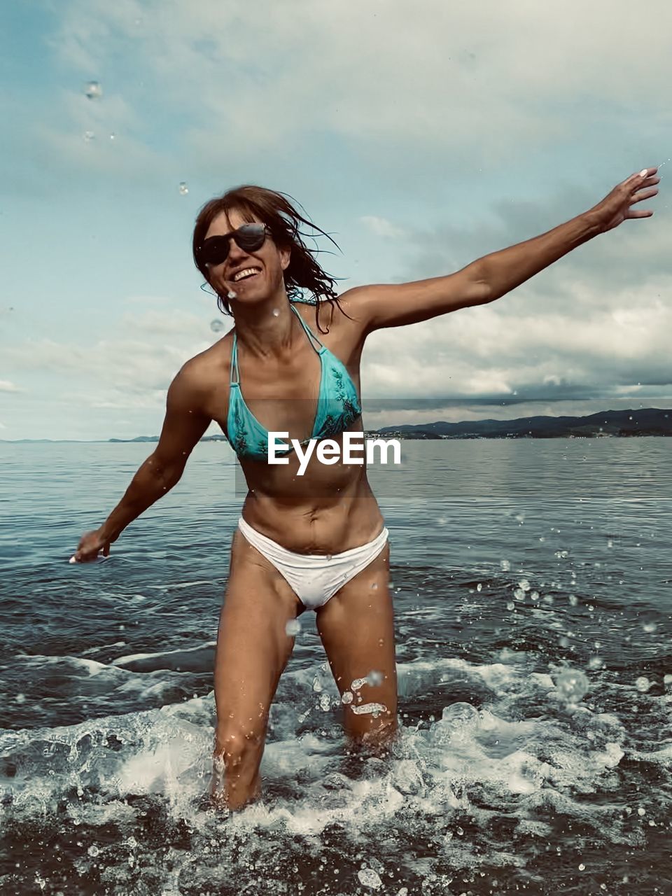 Portrait of smiling young woman in sea against sky
