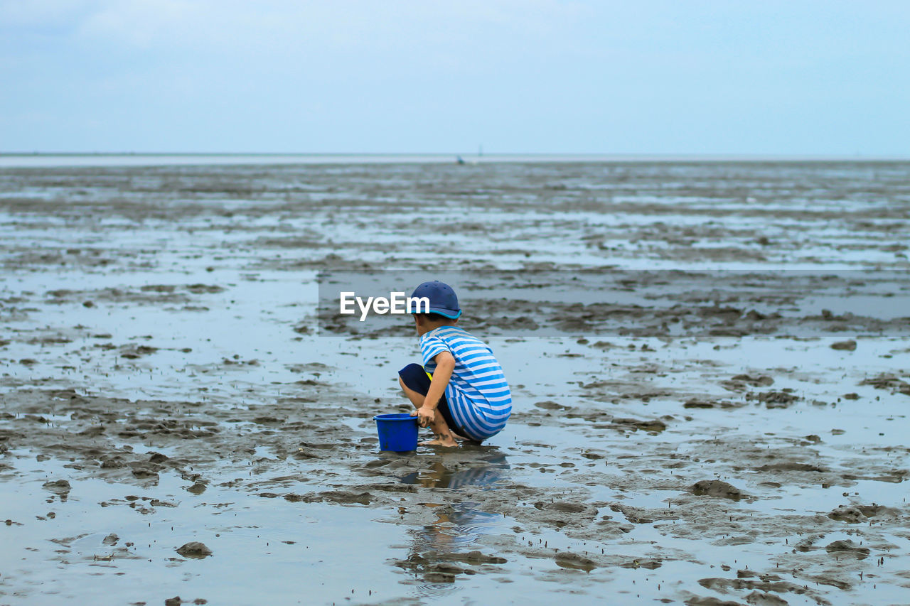 Boy playing with sand at beach