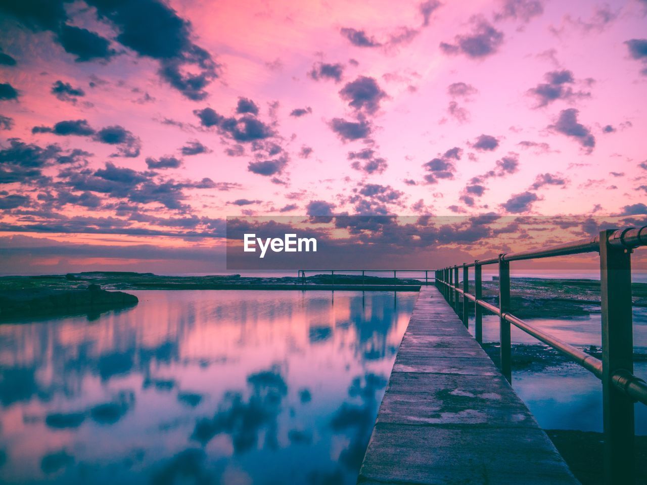 PIER AMIDST LAKE AGAINST SKY DURING SUNSET