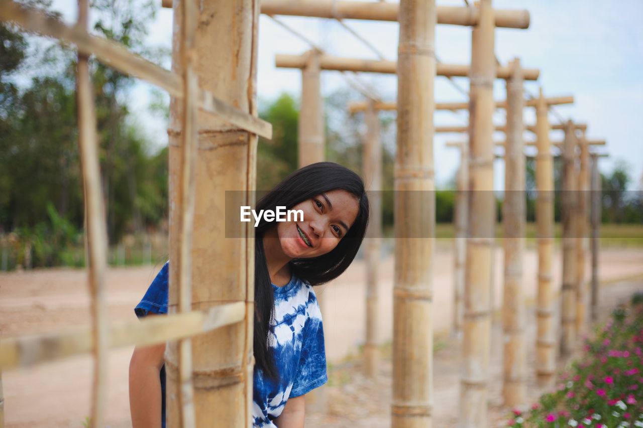 Portrait of smiling young woman by bamboo built structure