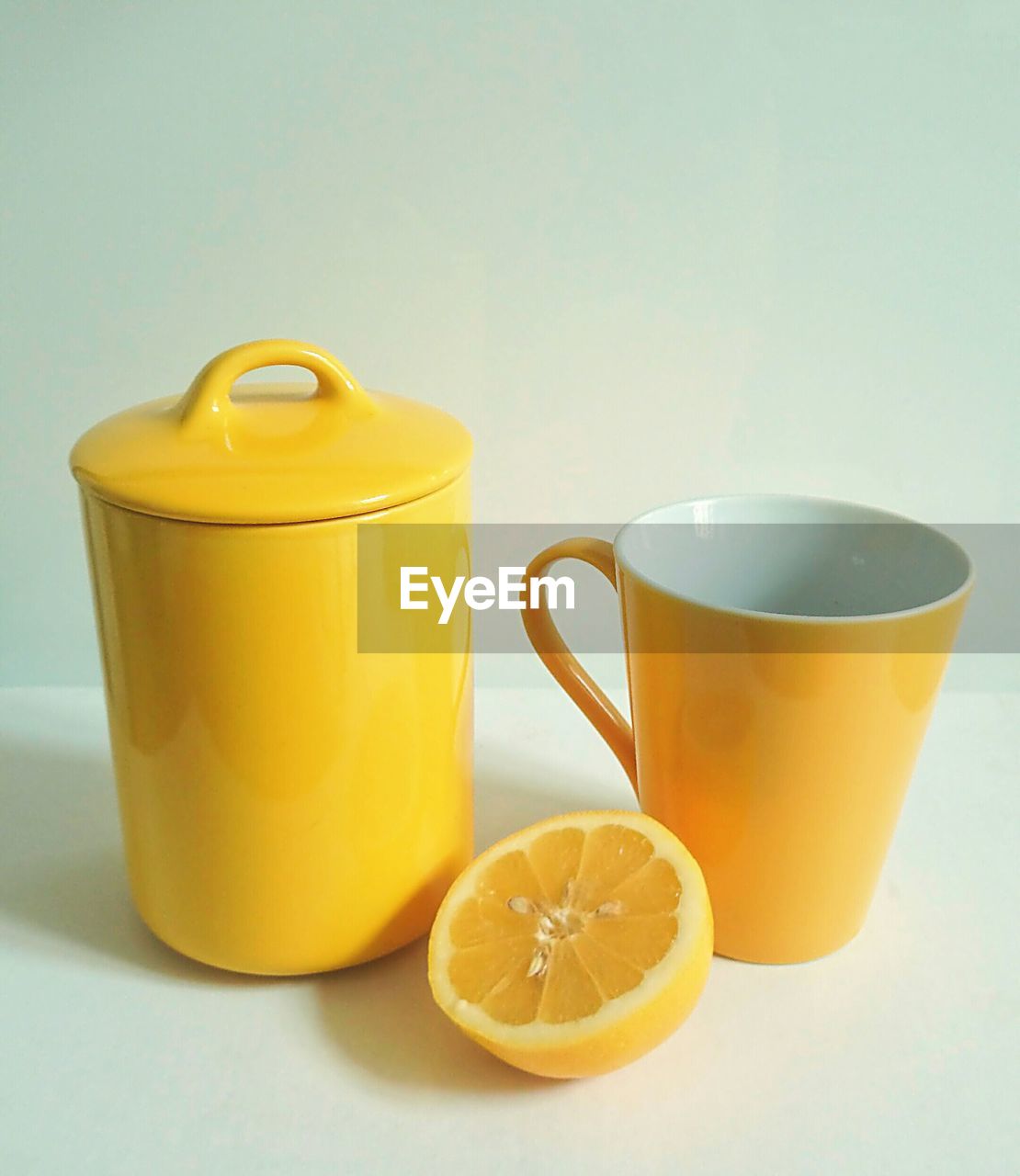 Halved sweet lime by coffee cup and jar on table