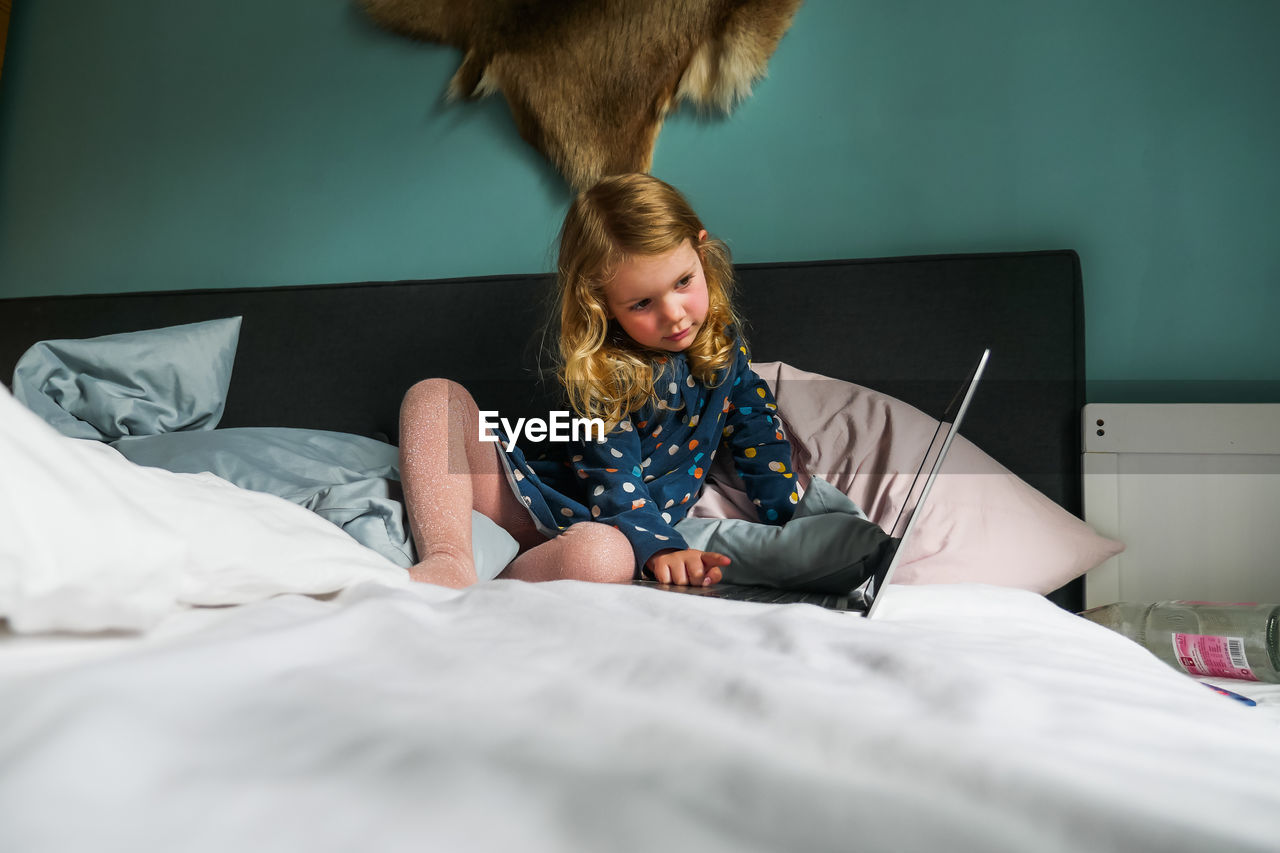 Cute girl using laptop while sitting at home