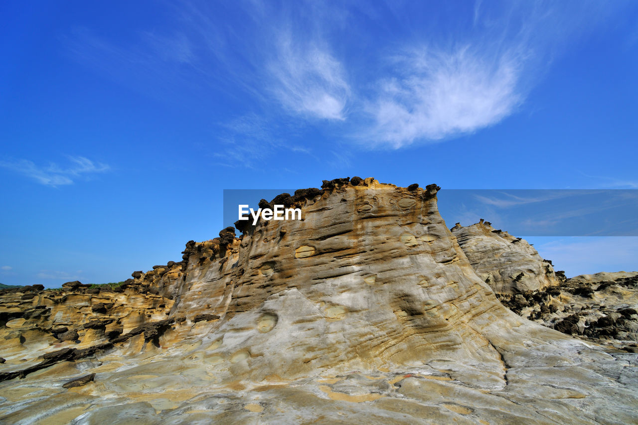 Rock formations on landscape against cloudy sky