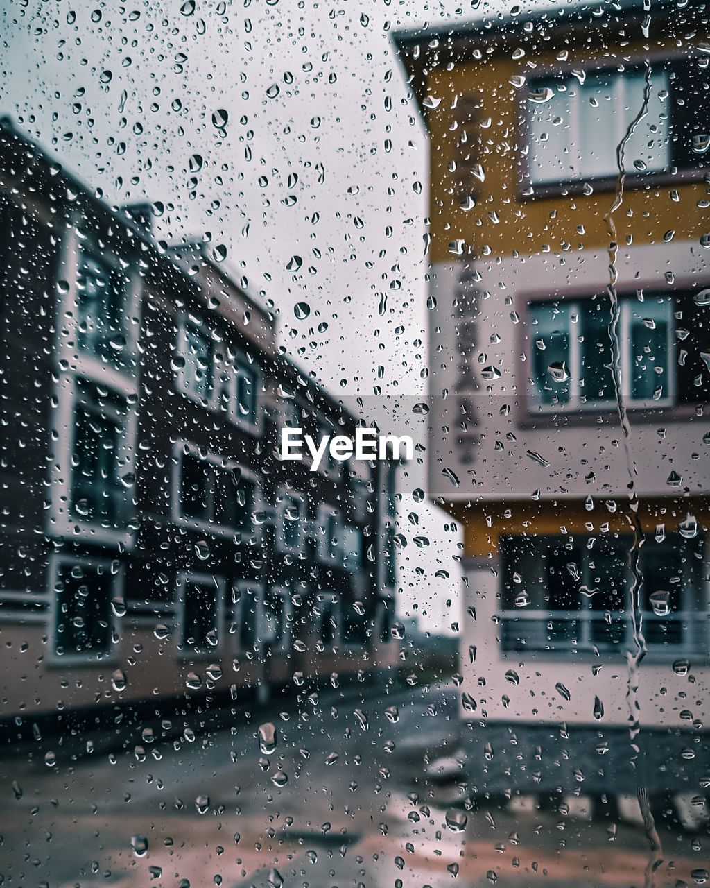 Buildings seen through wet glass window during rainy season