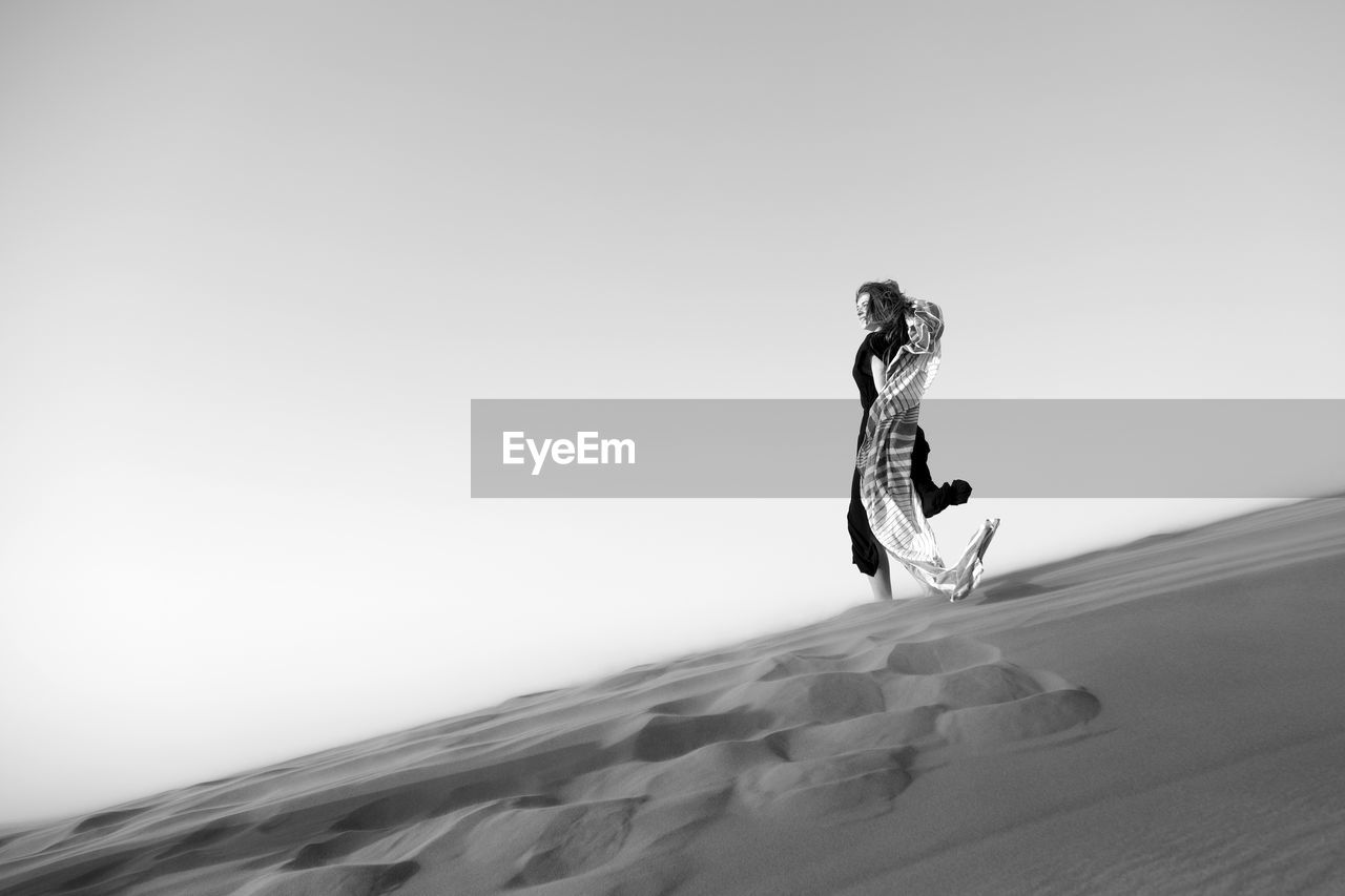 Full length of woman standing in desert against sky