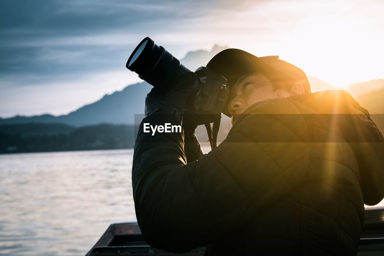 Man photographing with camera against sky