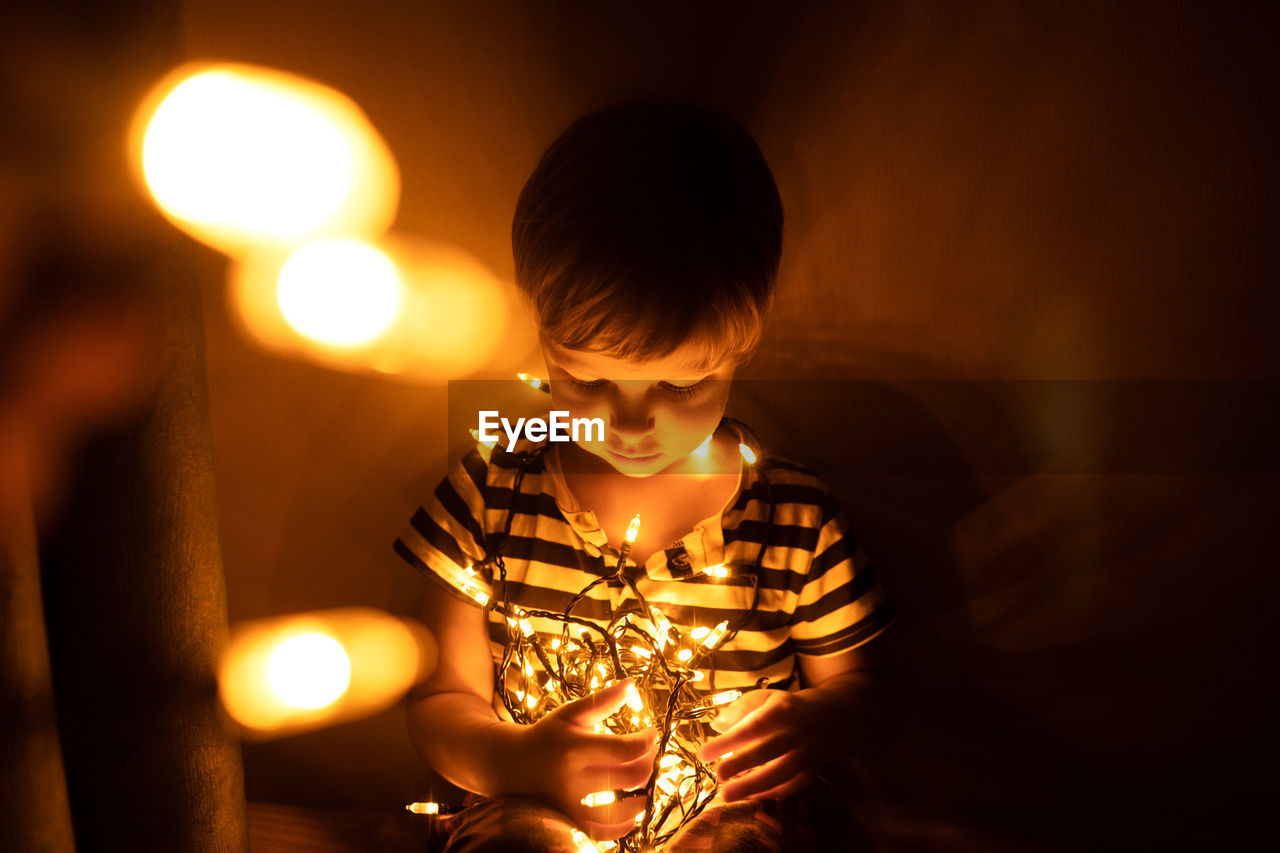 Full length of boy with illuminated lights at home