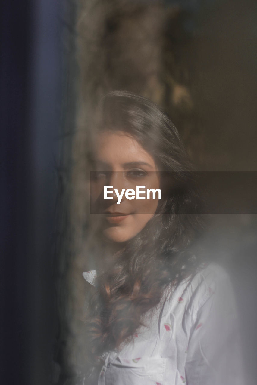 Portrait of smiling woman seen through window