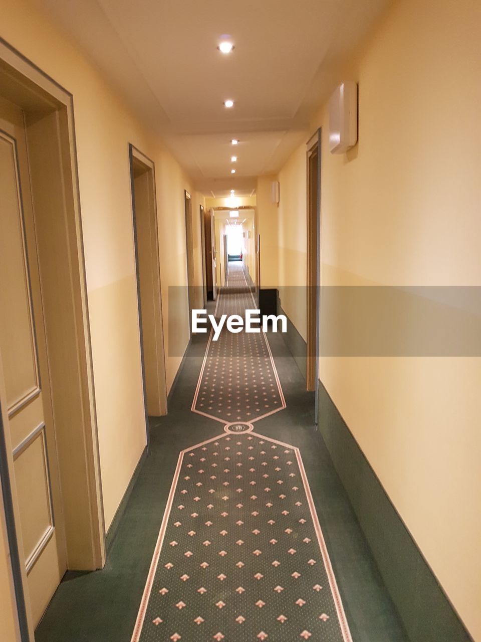 EMPTY CORRIDOR IN ILLUMINATED BUILDING