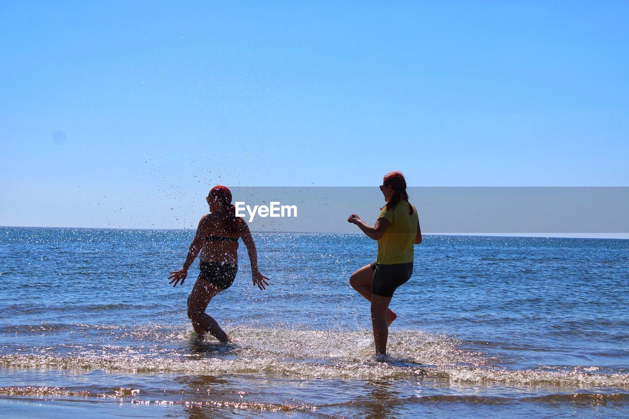 People on beach against clear sky