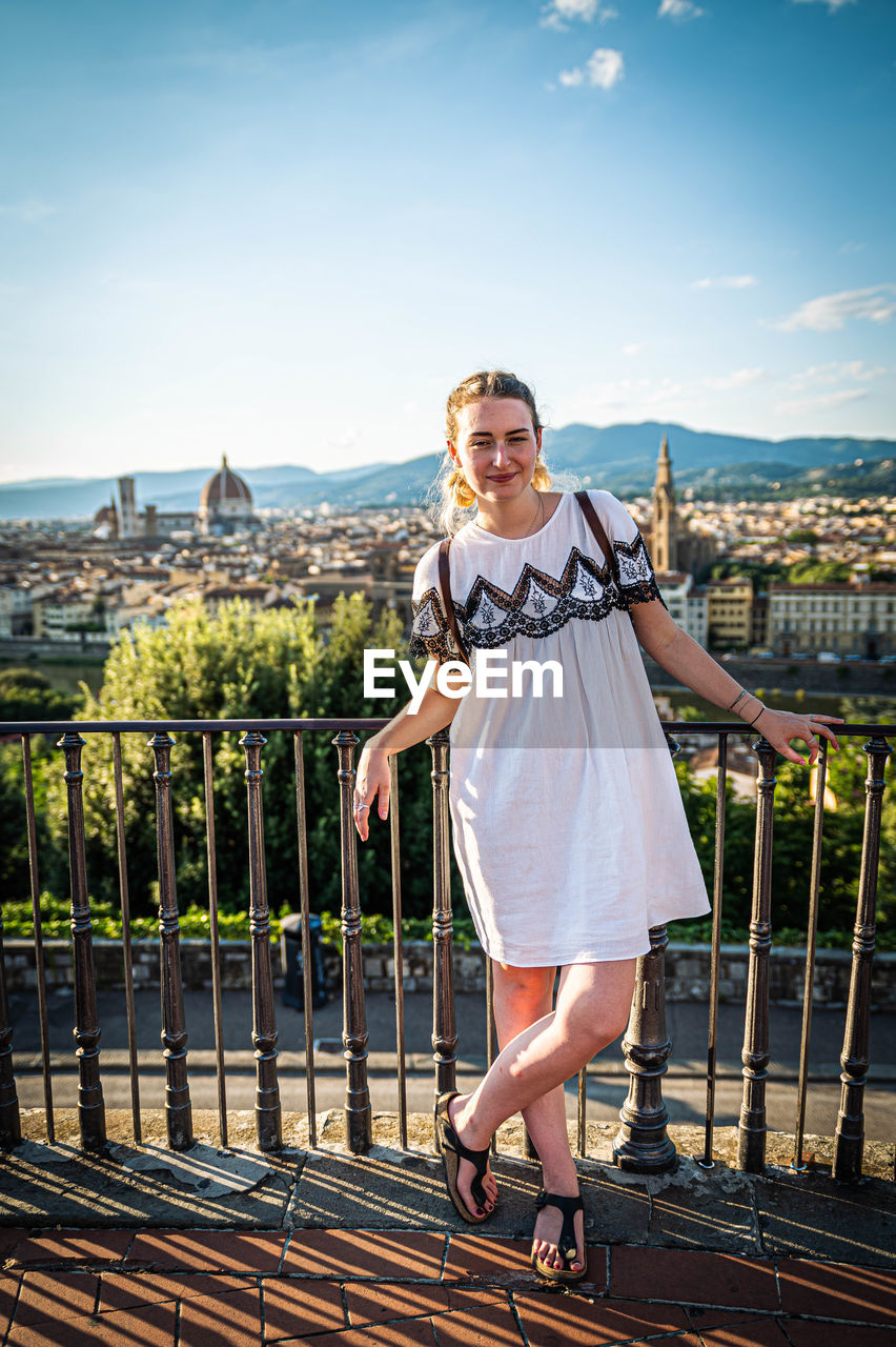 Portrait of smiling young woman standing against railing