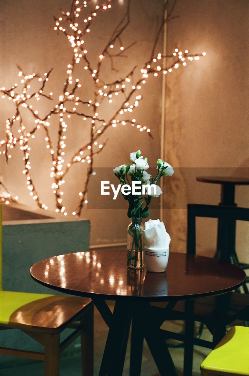 Flower vase on table at illuminated restaurant