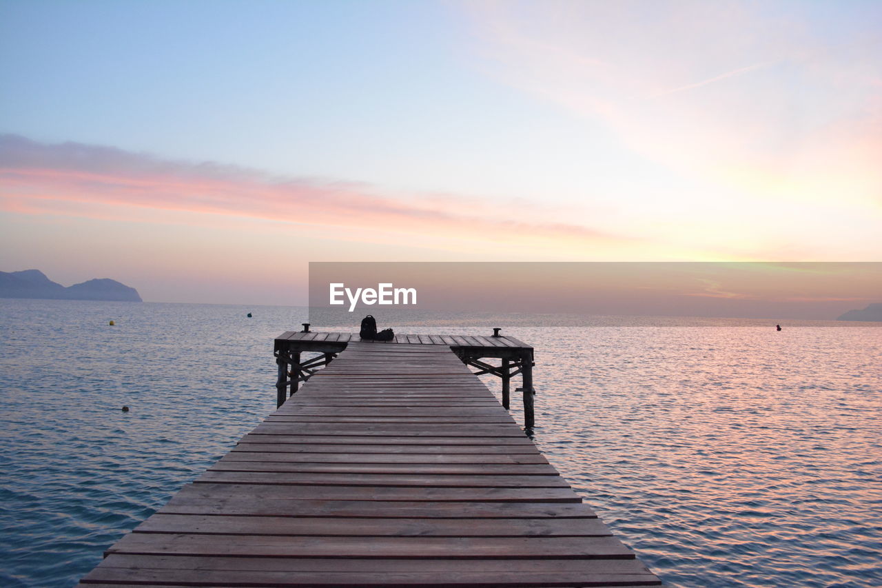 Pier over sea against sky during sunset