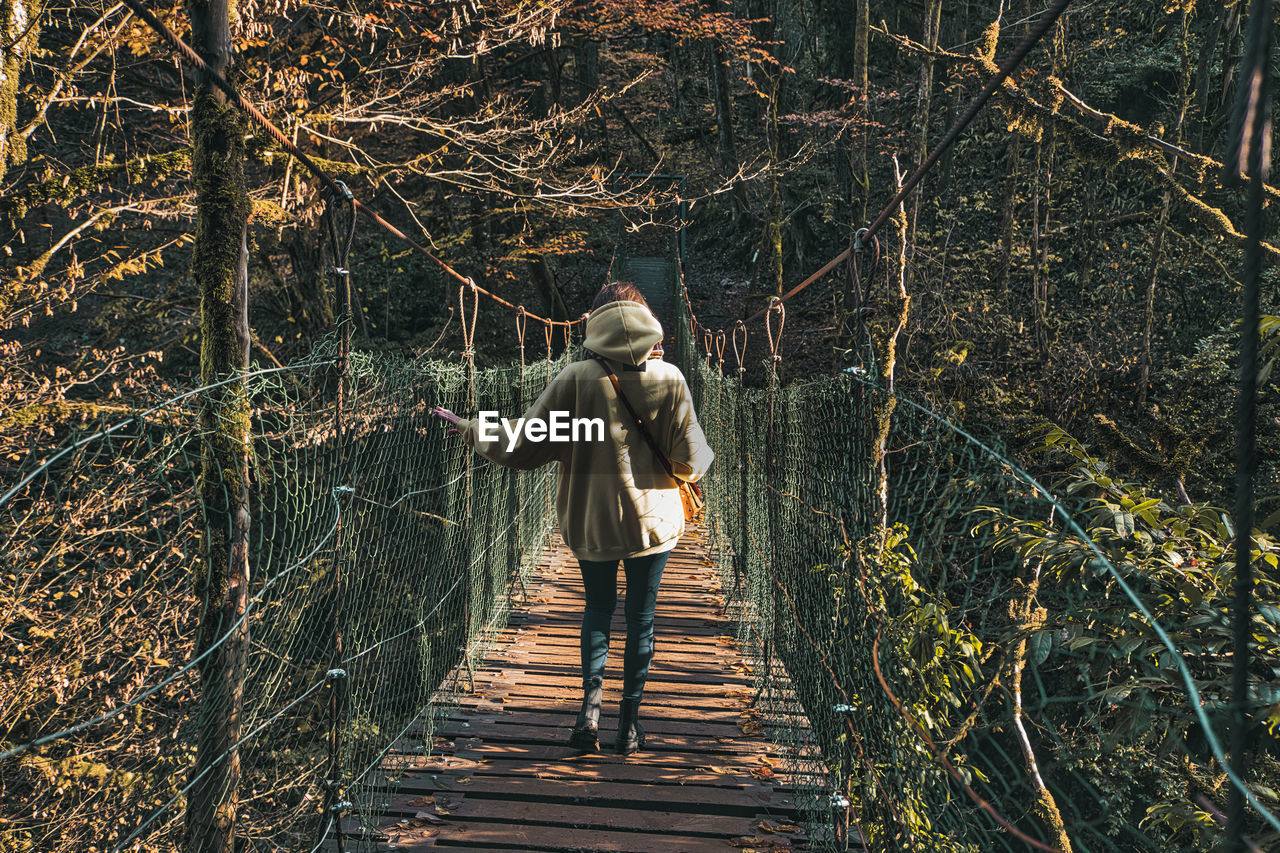 Young woman crossing suspension bridge