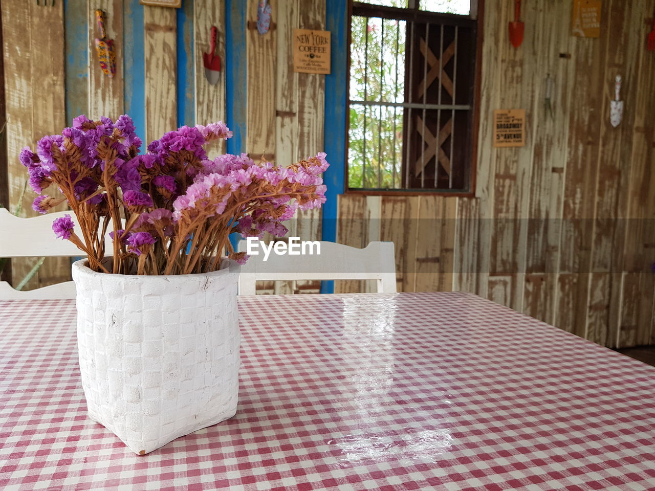 Purple flower vase on table against window