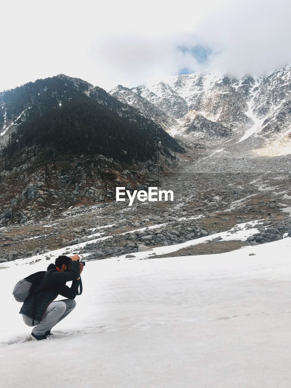 Man photographing on snowcapped mountain