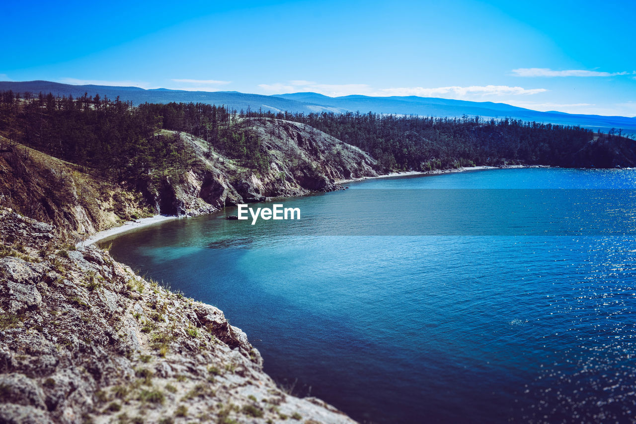 High angle view of river amidst mountains against blue sky